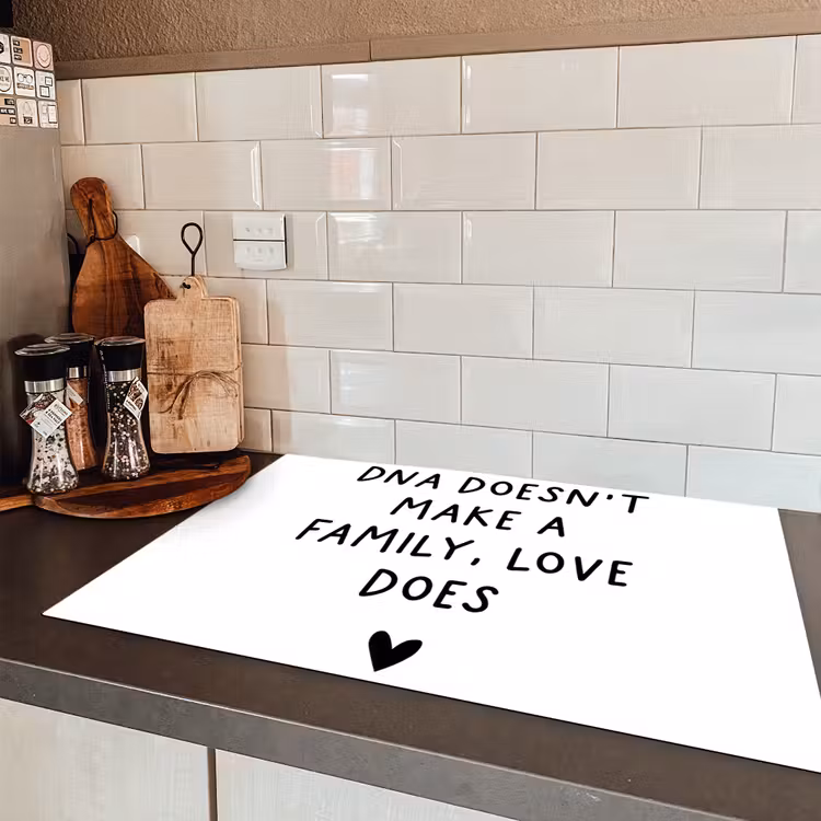 Engelse quote "DNA doesn't make a family, love does" met een hartje op een witte achtergrond Inductie beschermer vinyl 3mm klein -sfeer3